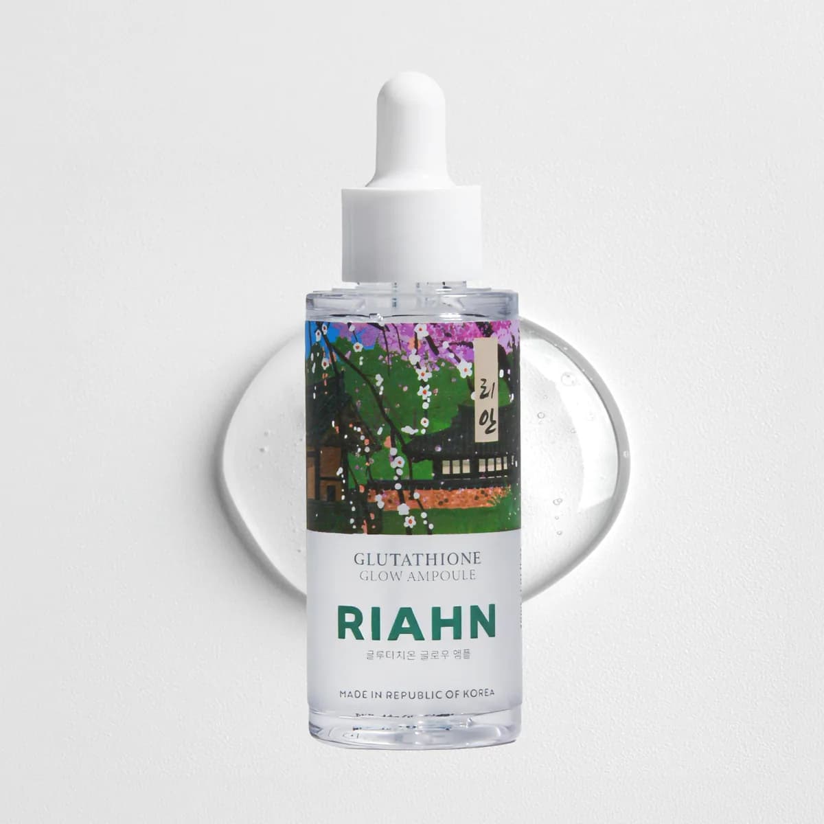 Glutathione Glow Ampoule: a glass dropper bottle in front of a round pool of clear gel, its village blossom label art behind it.