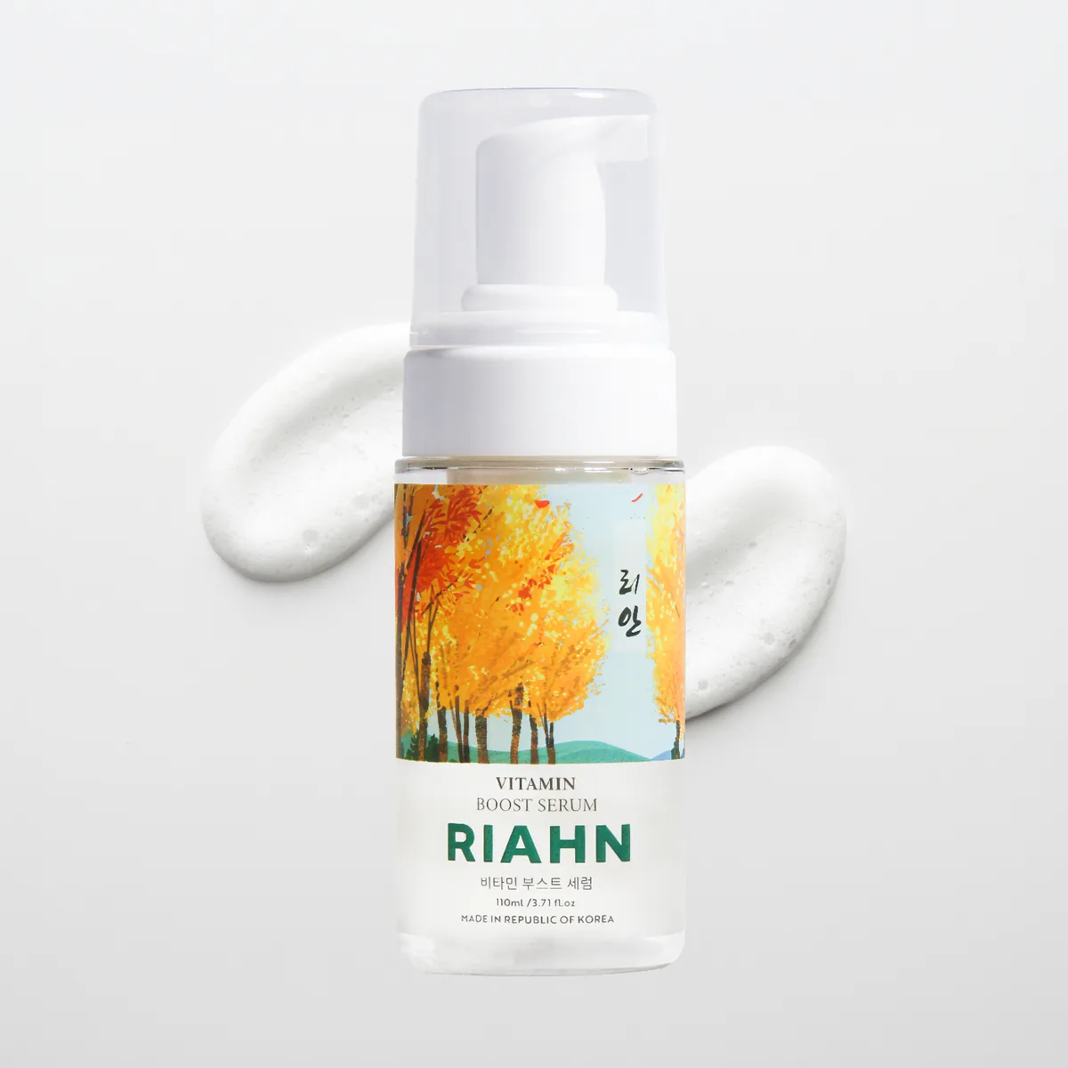 Vitamin Boost Serum: a pump bottle in front of a smear of white foam, its autumn-tree label art on the bottle.